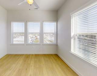 A room with a ceiling fan and two windows.