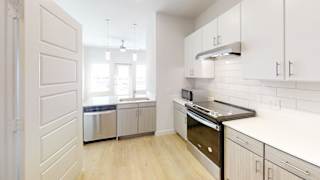 A modern kitchen with white cabinets and a wooden floor. at Park South Apartments, Austin, 78748