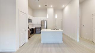 Modern kitchen with white island and pendant lighting at Cantarra Apartments, Texas, 78653