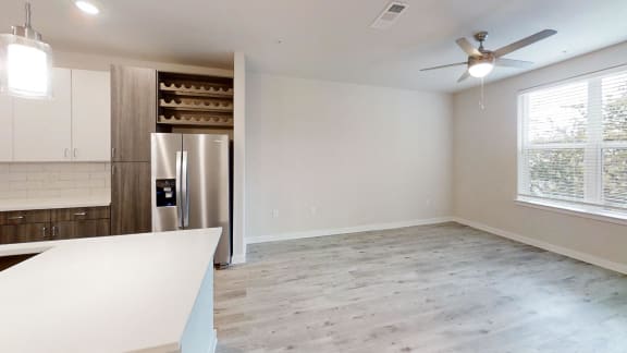an empty kitchen and living room with a stainless steel refrigerator