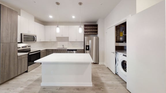 a white kitchen with stainless steel appliances and a white counter top