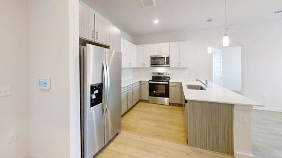 A modern kitchen with a refrigerator, microwave, oven, and sink.