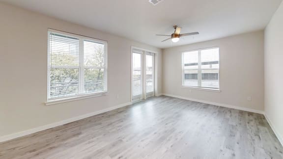 an empty living room with windows and a ceiling fan