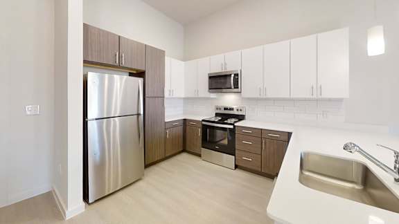 A modern kitchen with a stainless steel refrigerator and a white sink.