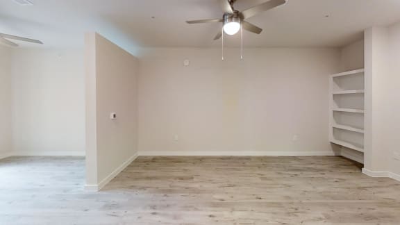 an empty room with white shelves and a ceiling fan