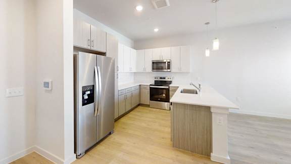 A modern kitchen with a stainless steel refrigerator and wooden flooring. at Park South Apartments, Texas
