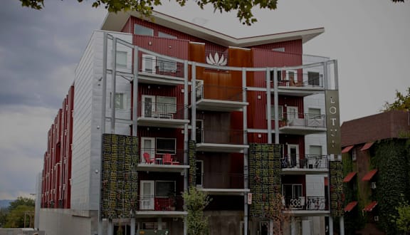 A red and white building with balconies and a tree in front.