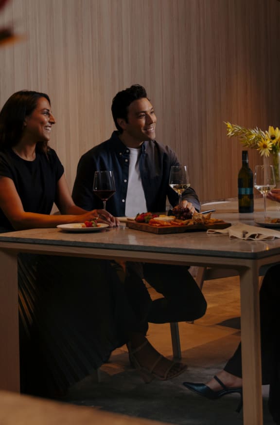 a group of people sitting around a table eating and drinking wine