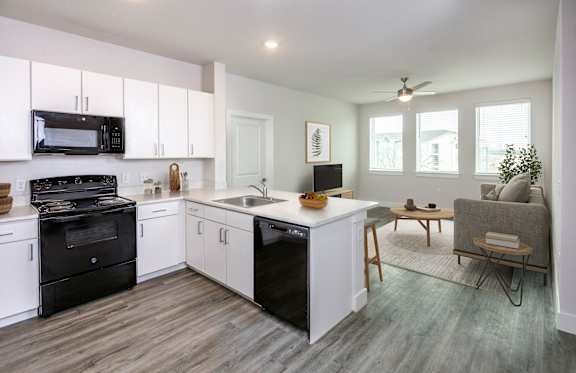 A modern kitchen with black appliances and white cabinets.