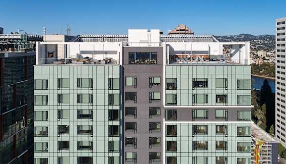 A modern building with glass windows and balconies is seen from a high vantage point.