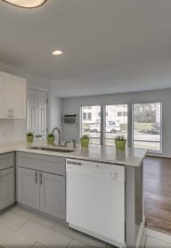 an empty kitchen with white appliances and white cabinets