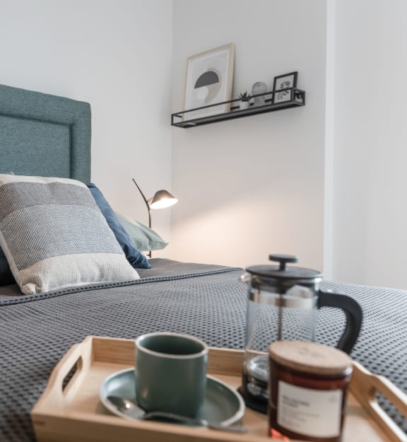 a bed with blue pillows and a tray with a cup of coffee