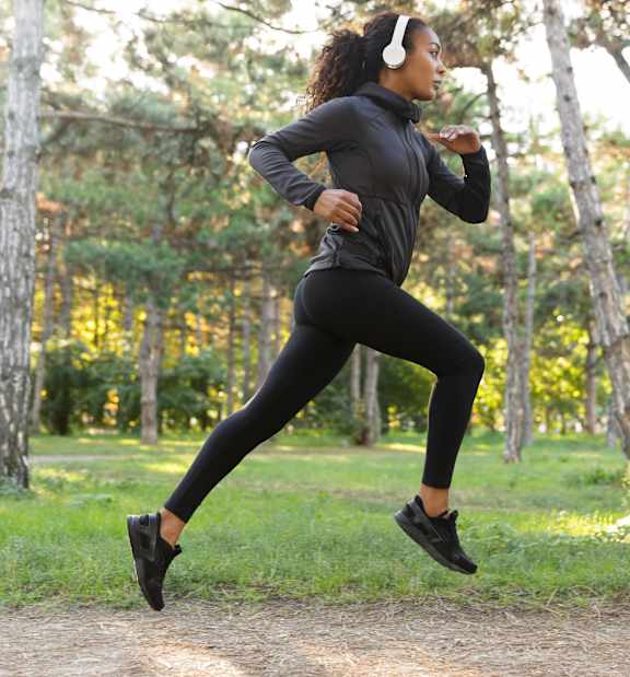 A woman running on a trail in the woods.
