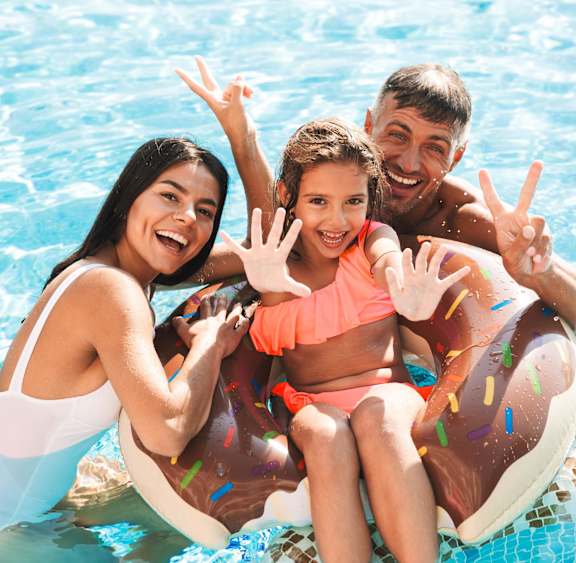 A family of three is enjoying their time in a pool.