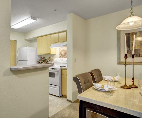 A kitchen with a stove and sink and a dining room with a table at Allegro Apartments. 