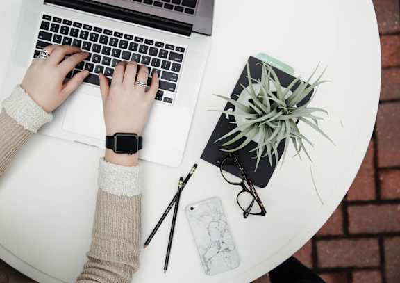 A person is typing on a laptop with a smartwatch on their wrist.