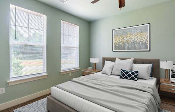 A bedroom with a bed, two lamps, and a painting on the wall.