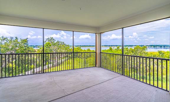 A balcony with a view of a green landscape and a body of water.