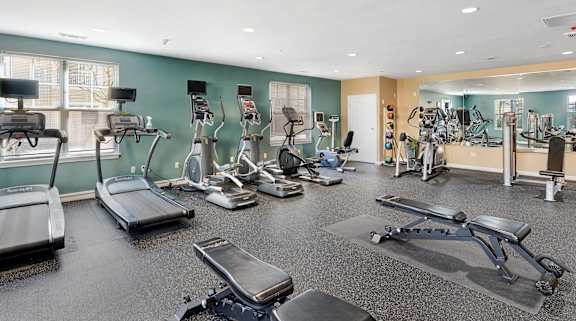 A gym with treadmills, exercise bikes, and other equipment at Parkside Commons