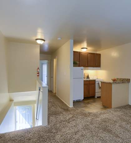 a living room and kitchen with carpeted floors and white walls