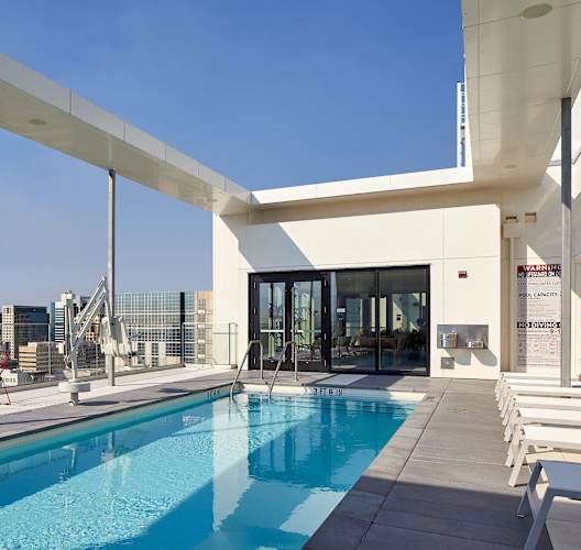 A pool area with a white building and red chairs.