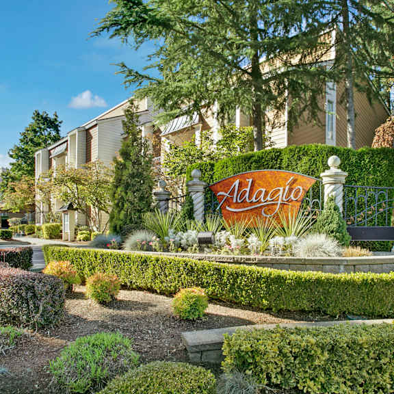 Front sign at Adagio surrounded by plants. 