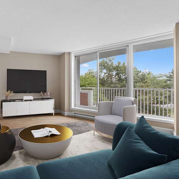 A living room with a grey couch, a round table, and a television.