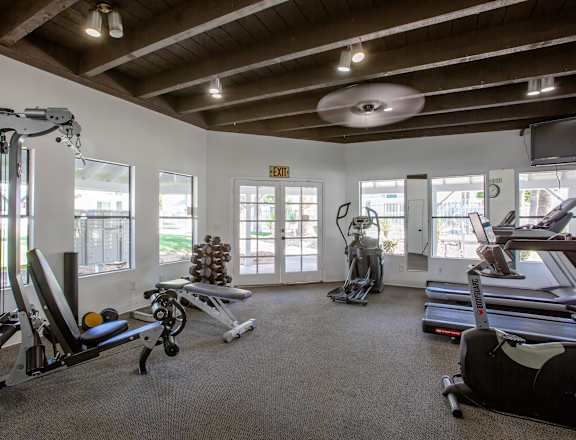 A gym with a variety of equipment including treadmills, weights, and exercise machines.