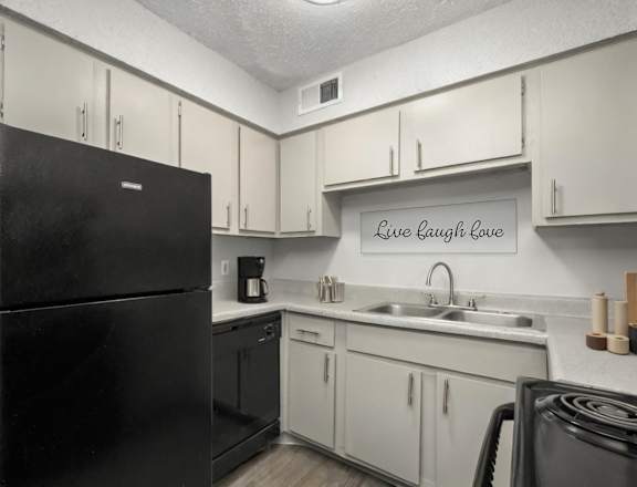 A black refrigerator in a kitchen with a sign that says Live Laugh Love.