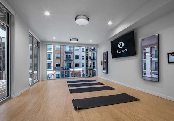a yoga room with yoga mats on the floor and a large screen on the wall at 2929 on Mayfair, Wauwatosa, WI, 53222
