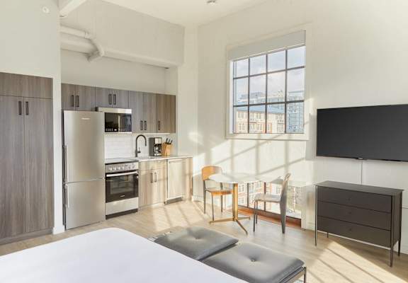 a studio apartment with a kitchen and a bed and a table and chairs