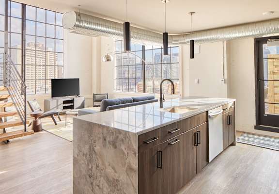 a kitchen with an island and a living room with a couch and a tv