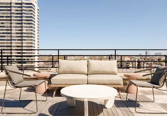 a furnished patio with a couch and tables on a balcony
