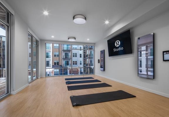a yoga room with yoga mats on the floor and a large screen on the wall