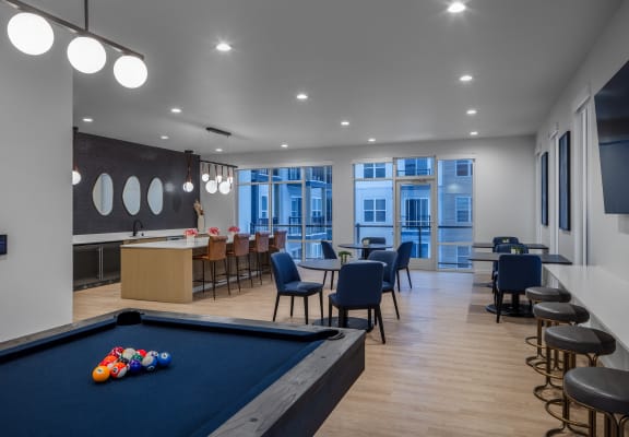 a communal area with a pool table and tables and chairs and a bar