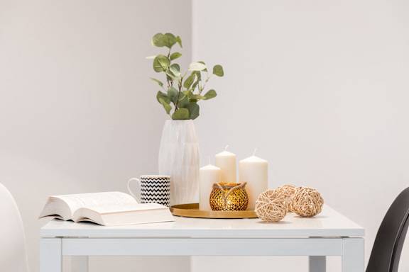 a white desk with a vase and candles on it
