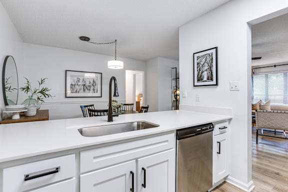 a kitchen with white cabinets and a sink and a dishwasher