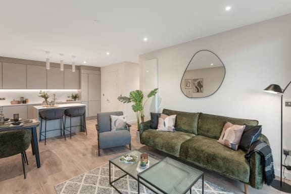 a living room with a green couch and a kitchen with a table and chairs