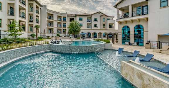 A large swimming pool in front of apartment buildings.