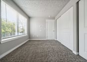 Thumbnail 7 of 8 - A room with white doors and carpeted floor.