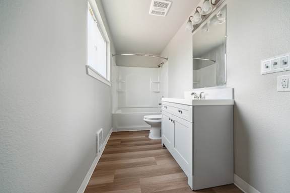 A white bathroom with a toilet, sink, and mirror.