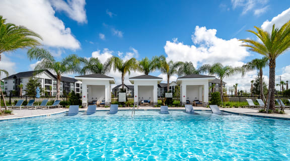a large swimming pool with palm trees and buildings in the background