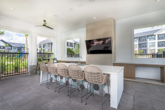 a kitchen with a bar and chairs and a television