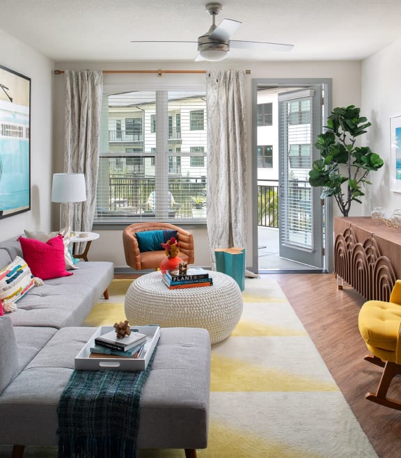 a living room with a gray couch and a large window at The District at Rosemary, Florida
