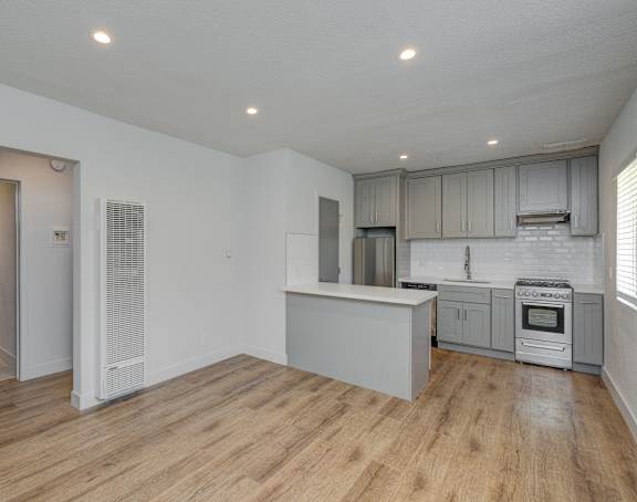 A kitchen with a white fridge, white cabinets, and a white oven.