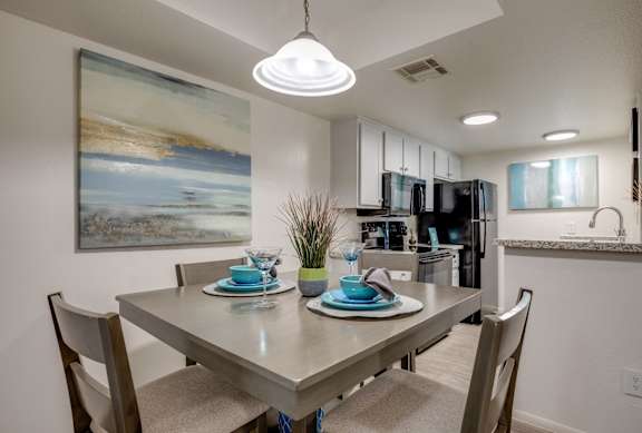 a kitchen and dining room area with a table and chairs and a refrigerator and microwave