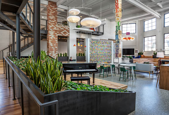A modern office space with a piano, chairs, and a green planter.