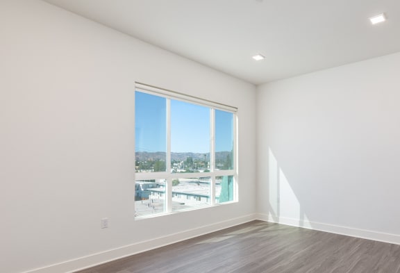 an empty living room with a window and wood flooring