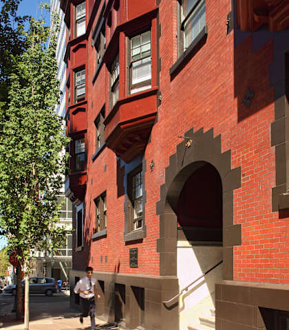 A man is walking on a sidewalk next to a red brick building.