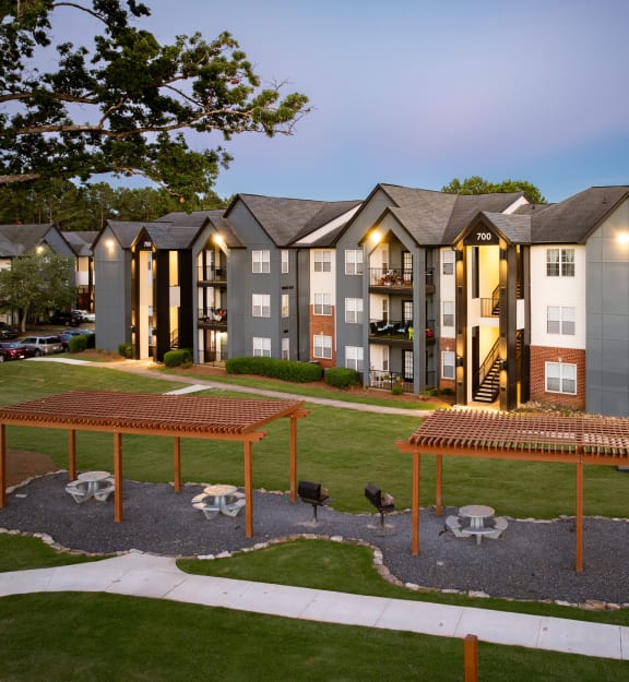 an exterior view of an apartment building with a courtyard and picnic tables
